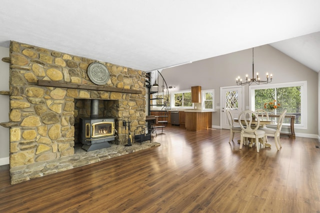 dining space with lofted ceiling, wood finished floors, a wood stove, baseboards, and a chandelier