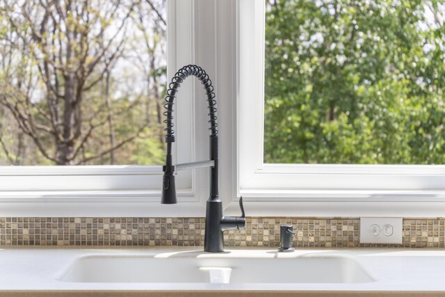 interior details with decorative backsplash, a sink, and light countertops
