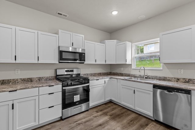 510 N Henry St, Mansfield, MO 65704 - kitchen featuring wood finished floors, a sink, appliances with stainless steel finishes, white cabinetry, and visible vents