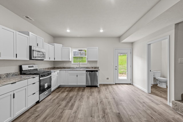 510 N Henry St, Mansfield, MO 65704 - kitchen featuring a sink, light wood-type flooring, white cabinets, appliances with stainless steel finishes, and light stone countertops