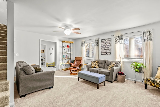 living room with carpet floors, baseboards, a ceiling fan, and stairs