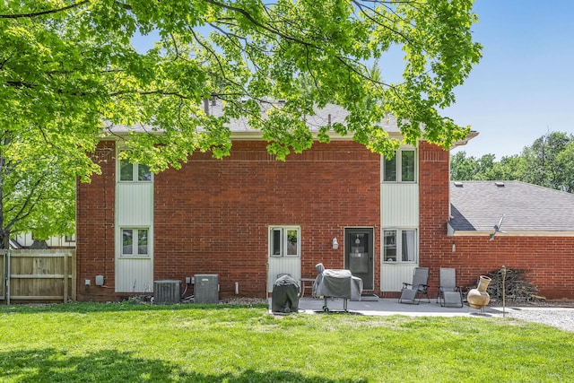 back of house with fence, central AC, a shingled roof, a patio area, and a lawn