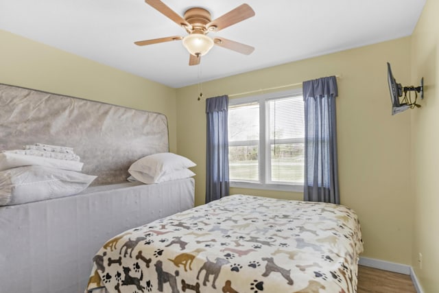 bedroom with wood finished floors, baseboards, and ceiling fan