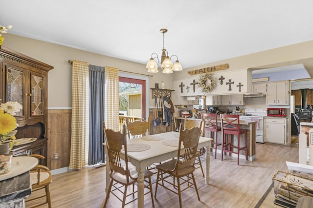 dining area with light wood-style flooring and a notable chandelier