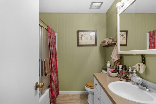 bathroom with enclosed tub / shower combo, toilet, vanity, and wood finished floors