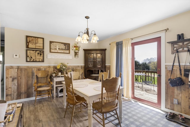 dining area with a wainscoted wall, wood finished floors, and an inviting chandelier