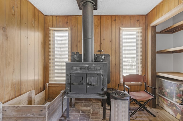 sitting room featuring a textured ceiling, a wood stove, and wood walls