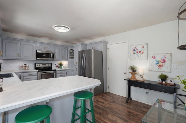 625 Parkwood Dr, Mount Vernon, MO 65712 - kitchen with stainless steel appliances, gray cabinetry, a peninsula, a breakfast bar area, and dark wood-style flooring