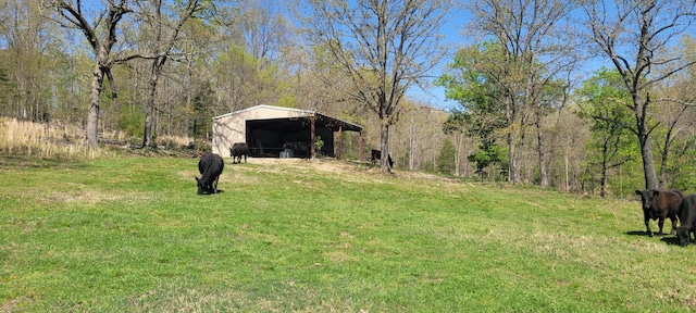 view of yard featuring a forest view, an outbuilding, a carport, and a pole building