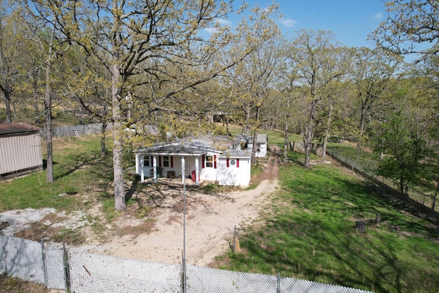 view of front of property featuring fence, dirt driveway, an outdoor structure, and covered porch