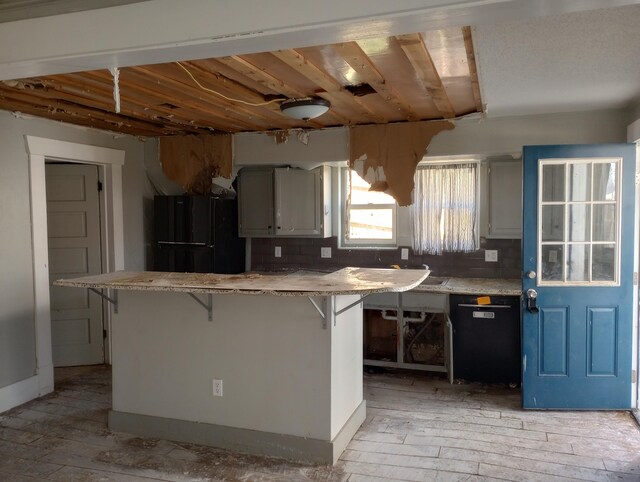 215 N Central Ave, Monett, MO 65708 - kitchen featuring a kitchen breakfast bar, light countertops, dishwashing machine, freestanding refrigerator, and light wood-type flooring