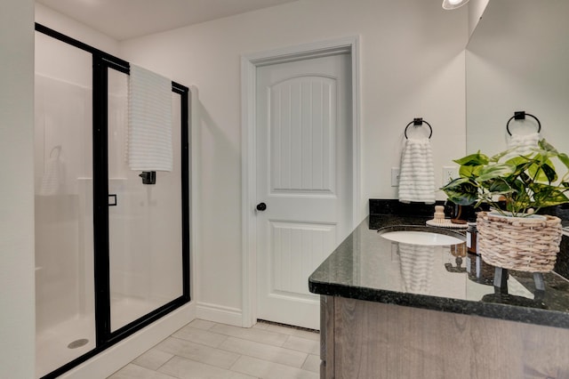 bathroom with baseboards, vanity, tile patterned flooring, and a stall shower
