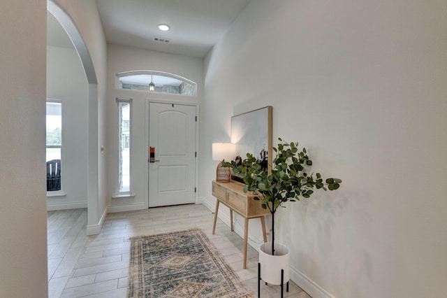 foyer entrance with arched walkways, visible vents, and baseboards