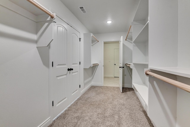 walk in closet with visible vents and light colored carpet