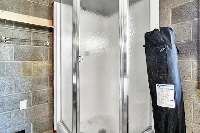 full bathroom featuring concrete block wall and a stall shower