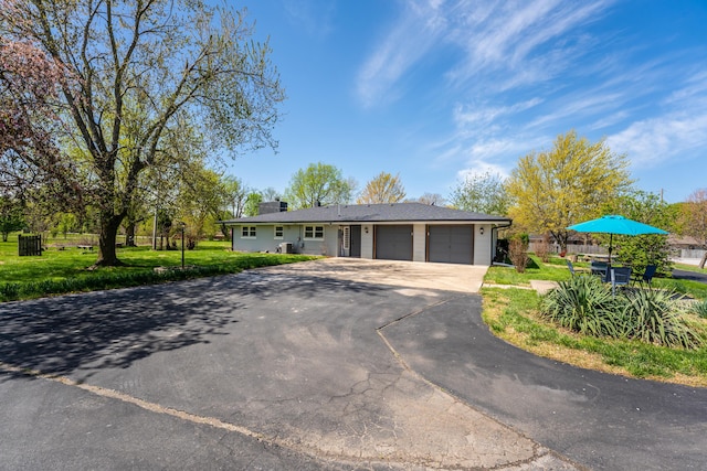 view of front of home with fence, a front lawn, aphalt driveway, and a garage
