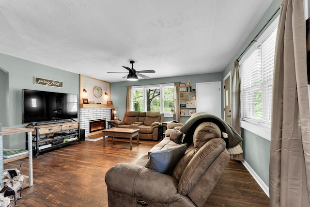 living room featuring a textured ceiling, baseboards, a ceiling fan, wood finished floors, and a fireplace