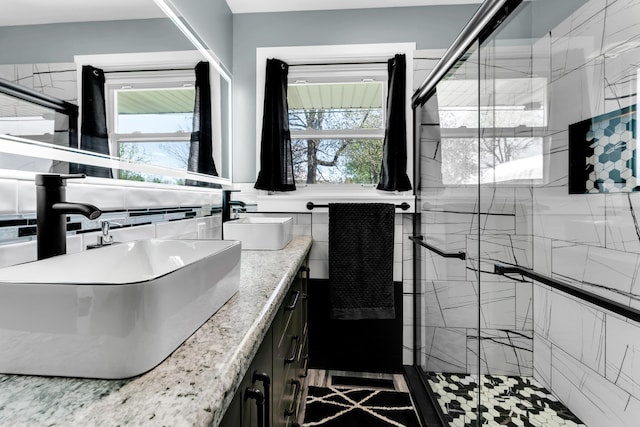 full bathroom featuring a shower stall, a sink, double vanity, and tile walls