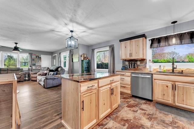 kitchen featuring a wealth of natural light, light brown cabinets, stainless steel dishwasher, and a sink