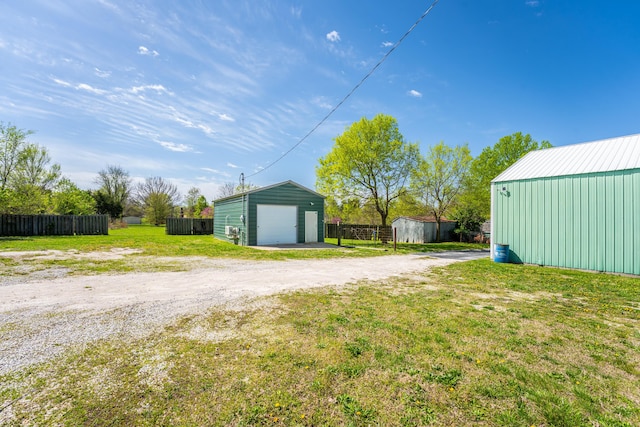 view of yard featuring a detached garage, a pole building, dirt driveway, an outdoor structure, and fence