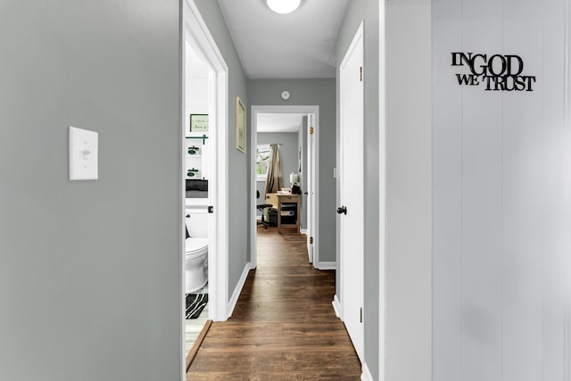 hallway featuring dark wood-type flooring and baseboards