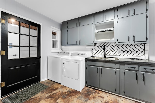 clothes washing area featuring cabinet space, stone finish floor, a sink, and independent washer and dryer