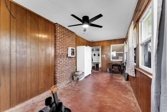 interior space featuring heating unit, wood walls, a ceiling fan, and finished concrete floors