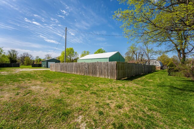 view of yard with fence, driveway, and a garage
