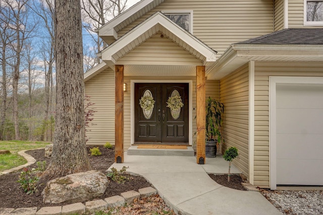 view of exterior entry featuring roof with shingles and a garage