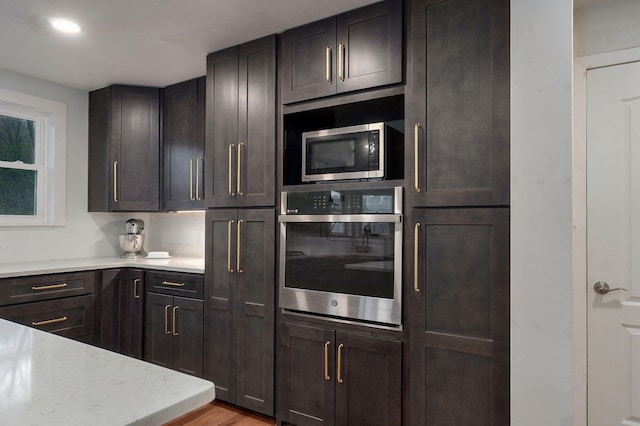 kitchen with light stone counters, wood finished floors, and stainless steel appliances