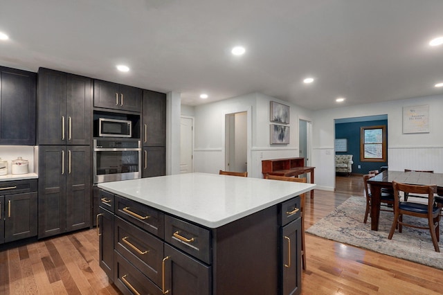 kitchen with a center island, recessed lighting, wood finished floors, light countertops, and appliances with stainless steel finishes