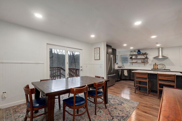 dining area featuring recessed lighting, light wood-type flooring, and a wainscoted wall
