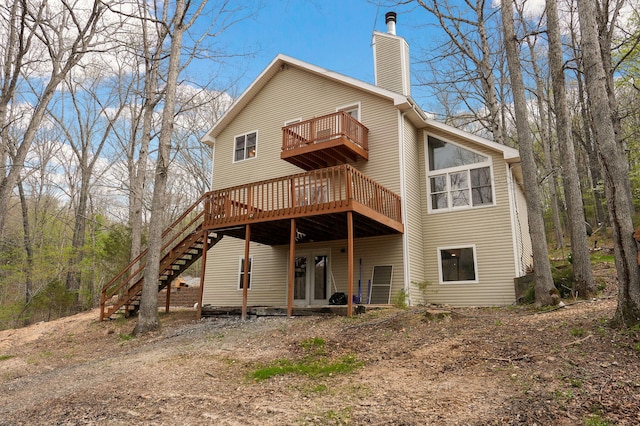 rear view of house with a chimney, stairs, a deck, and a balcony