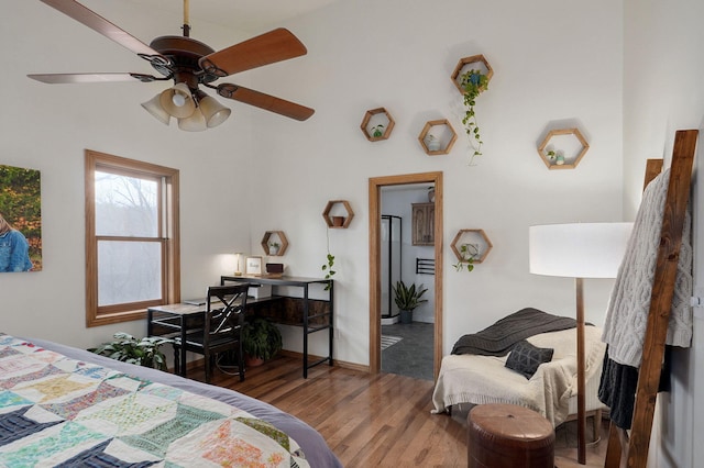 bedroom with wood finished floors, a towering ceiling, and ceiling fan