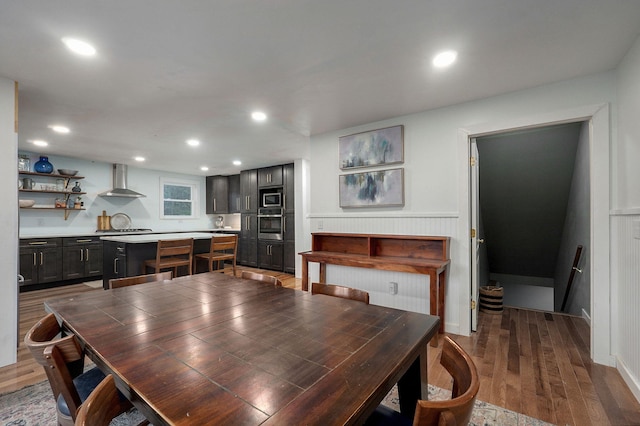 dining area with a wainscoted wall, wood finished floors, and recessed lighting