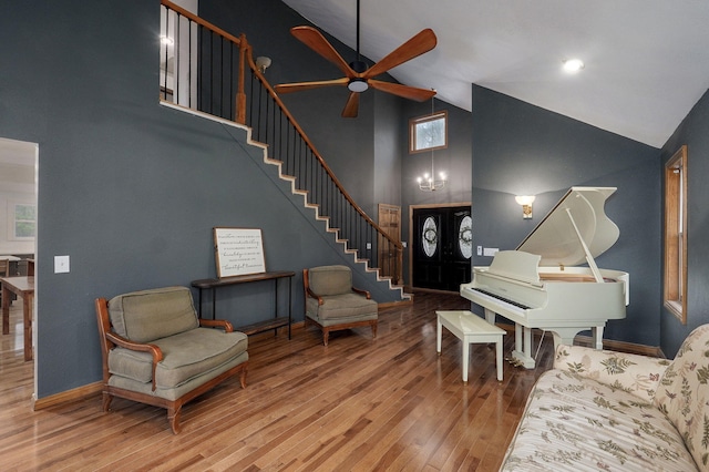 living room with high vaulted ceiling, a ceiling fan, stairs, wood finished floors, and baseboards