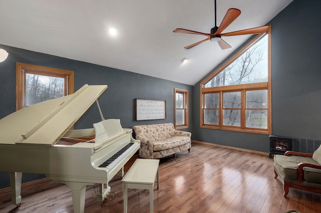 living area with hardwood / wood-style floors, a wood stove, ceiling fan, and plenty of natural light