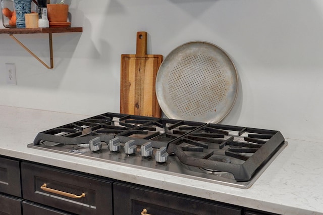 room details with dark brown cabinetry, light stone countertops, and stainless steel gas stovetop
