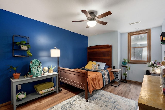 bedroom featuring baseboards, a ceiling fan, wood finished floors, and visible vents