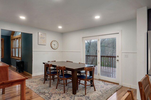 dining room with recessed lighting, wood finished floors, a wood stove, and wainscoting