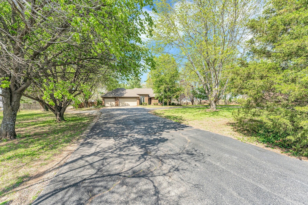 obstructed view of property with an attached garage, driveway, a front yard, and fence