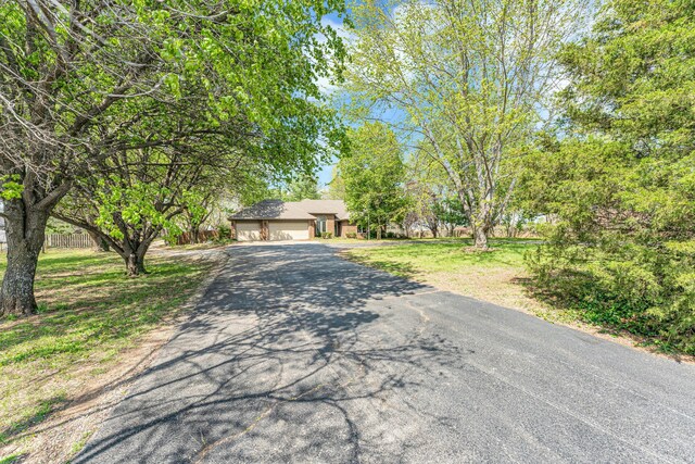 obstructed view of property with an attached garage, driveway, a front yard, and fence