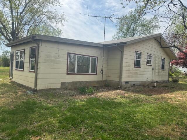 view of side of home with crawl space and a yard