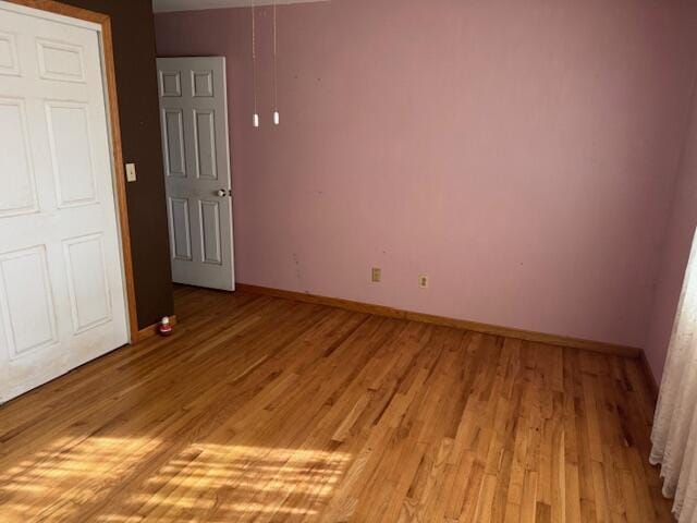 unfurnished room with baseboards and light wood-type flooring