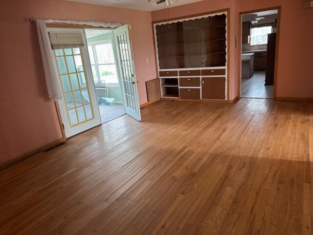 unfurnished living room featuring baseboards, a ceiling fan, visible vents, and light wood-style flooring