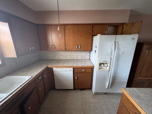 kitchen featuring tile counters, brown cabinetry, and white appliances