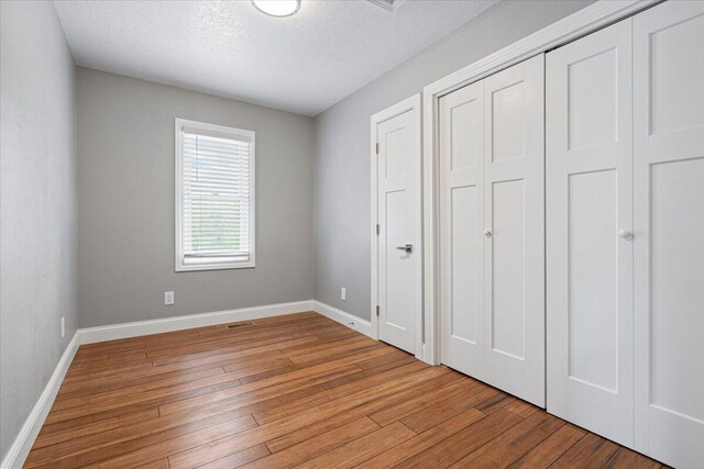 101 Poindexter Dr, Pineville, MO 64856 - unfurnished bedroom featuring a textured ceiling, light wood-style flooring, a closet, and baseboards