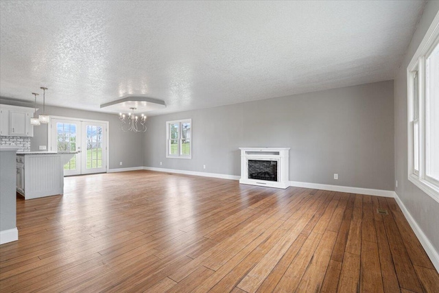 101 Poindexter Dr, Pineville, MO 64856 - unfurnished living room featuring wood finished floors, a textured ceiling, a chandelier, and a fireplace with raised hearth