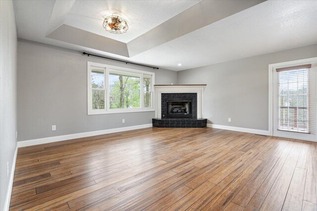 101 Poindexter Dr, Pineville, MO 64856 - unfurnished living room featuring a fireplace, hardwood / wood-style floors, baseboards, and a tray ceiling