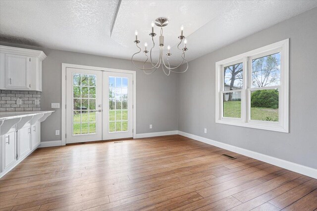 101 Poindexter Dr, Pineville, MO 64856 - unfurnished dining area with a chandelier, french doors, light wood-style flooring, baseboards, and visible vents